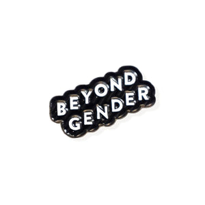 Enamel pin that reads "BEYOND GENDER" in white text angled diagonally upwards with a black border. 