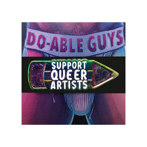 Enamel pin of a holographic pencil with text that reads "support queer artists" in white lettering in the middle of the pencil placed on a card of a man in a jockstrap with "doable guys" on the band. 