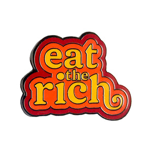 An enamel pin that reads "Eat the Rich" in 70's style yellow font outlined by orange and then red. 