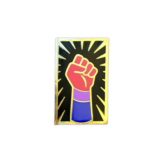 Enamel pin of a raised fist colored like the bisexual flag with gold outlining against a black background with a gold sunburst. 
