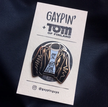 Load image into Gallery viewer, A picture of an enamel pin of a leather jacket with a white shirt with art of a shirtless man in black jeans and a conductor hat by Tom of Finland underneath on a white card with black text that reads &quot;Gaypin&#39; + Tom of Finland&quot; along the top.